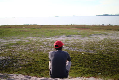 Rear view of man looking at field against sky