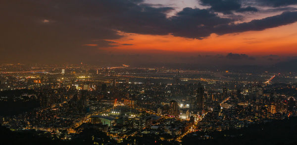 Aerial view of illuminated buildings against sky at night