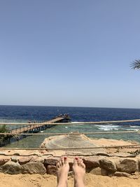 Low section of person on beach against clear sky