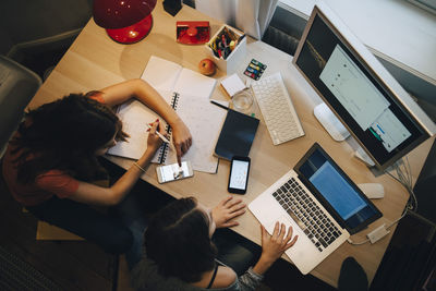 High angle view of friends using computer at table