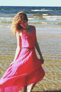 Woman looking down while walking on shore at beach