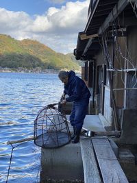 Mature woman holding lobster trap by lake