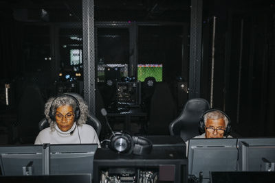 Elderly male and female friends playing video game on computers in gaming lounge