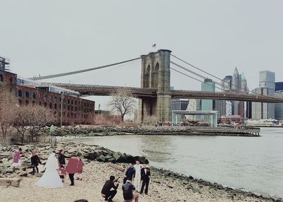 People walking on bridge over river against clear sky