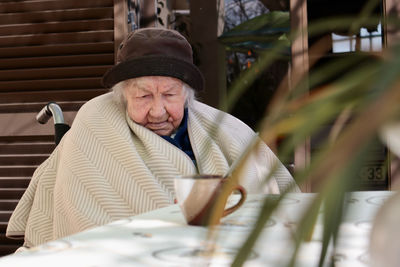 Senior woman sitting by table with coffee cup outdoors