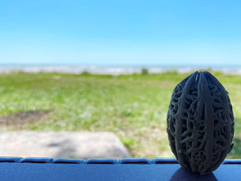 Close-up of tire track on field against blue sky