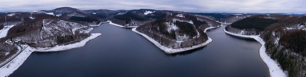 Panoramic view of lake by snowcapped mountains against sky