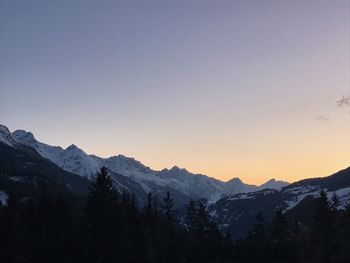 Scenic view of snowcapped mountains against clear sky during sunset