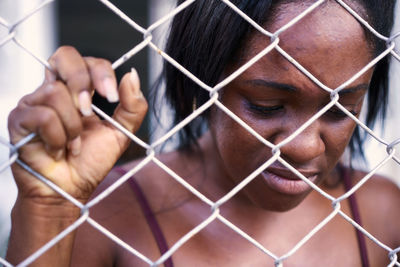 Portrait of young man holding chainlink fence