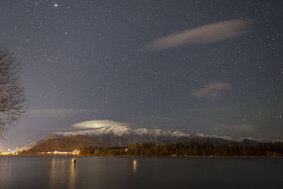 Scenic view of lake and mountains against sky at night