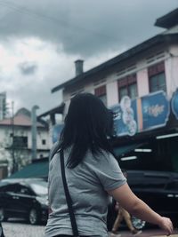 Rear view of woman standing on street against sky