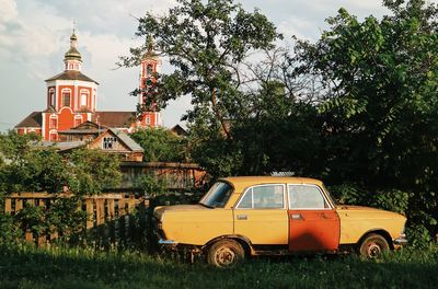 Vintage car against trees and building against sky