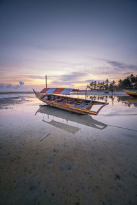 Boats moored on beach against sky during sunset