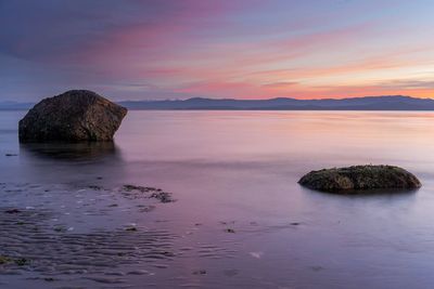 Headlands in calm sea against the sky