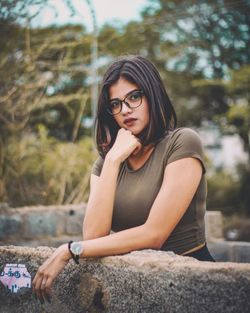 Portrait of beautiful young woman sitting on tree