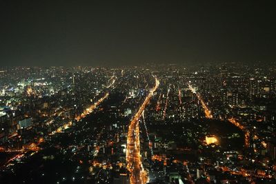 Aerial view of illuminated buildings against clear sky at night in city