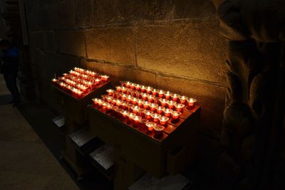 High angle view of lit tea light candles arranged against wall in church