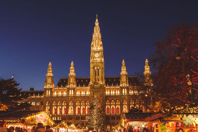 Illuminated new town hall and christmas market against clear blue sky
