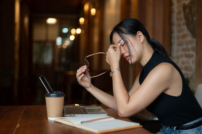 Young woman using mobile phone while sitting at restaurant