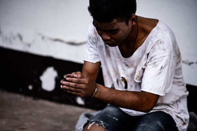 Midsection of man sitting against wall