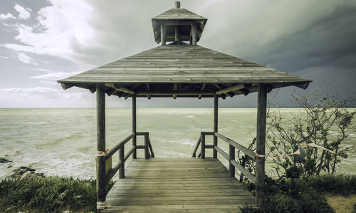 Pier leading towards sea against sky