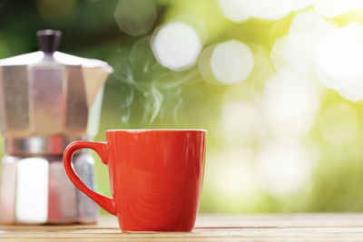 Red cup of coffee with nature green background