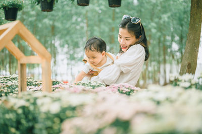 Mother and son standing by flowering plants