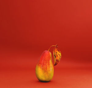 Pear with yellow leaf on beige background. autumn mood. bold hues for basis designs