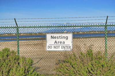 Information sign on fence against clear sky