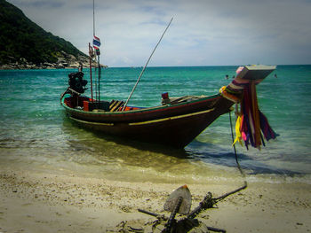 Boat moored on beach against sky