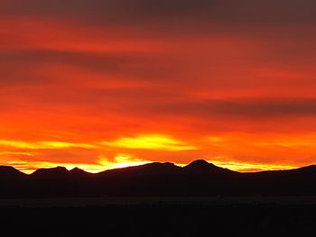 Scenic view of silhouette mountains against orange sky