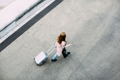 Top view of walking woman with wheeled luggage