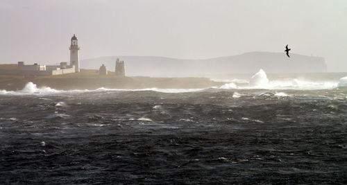 Sea waves splashing on shore against clear sky