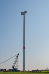 Low angle view of crane against clear blue sky