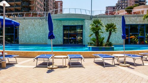 Chairs by swimming pool against building