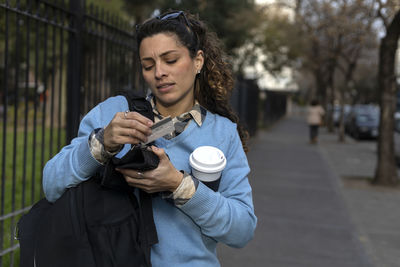 Portrait of young woman drinking milk while standing outdoors