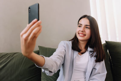 Portrait of smiling young woman using mobile phone