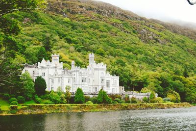 Scenic view of river by buildings against mountain