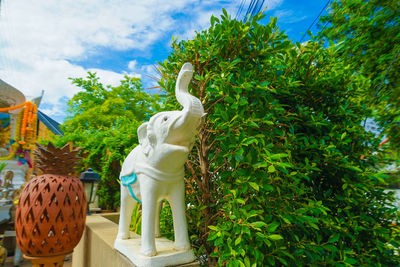 Statue against trees and plants against sky