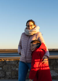 Mother and son cuddling on a rooftop wearing a jacket