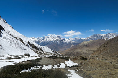 Scenic view of snowcapped mountains against blue sky