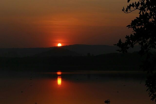 sunset, tranquil scene, sun, silhouette, scenics, tranquility, beauty in nature, orange color, mountain, water, idyllic, sky, nature, reflection, mountain range, landscape, sunlight, majestic, lake, non-urban scene