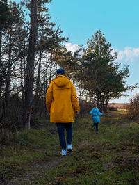 Travelers father daughter walking together pine forest enjoy scenic landscape back view hiking trail