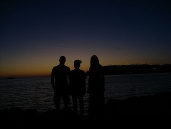 Silhouette of friends standing on beach