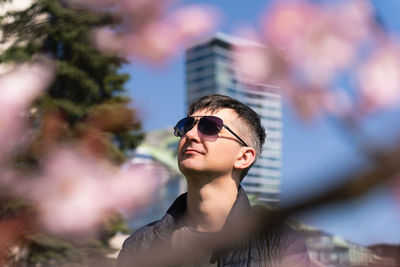 Man enjoying cherry blossom while walking during lunch break in city park in spring