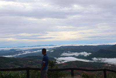 Rear view of man standing on mountain against sky