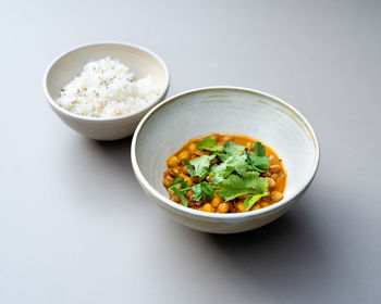 Vegan curry bowl with rice standing on grey table top view