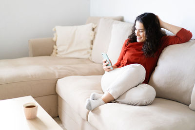 Young woman sitting on sofa at home
