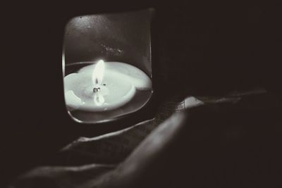 Close-up of lit candle in darkroom