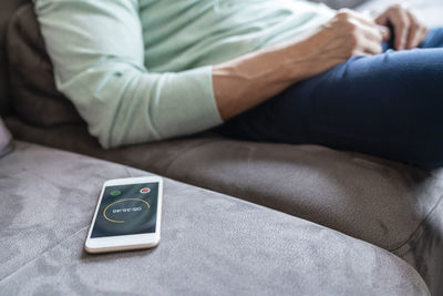 Smart phone with timer by man sitting on sofa at home